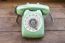 green-vintage-telephone-on-brown-wood-desk-background_BwJxPaeu3Gx